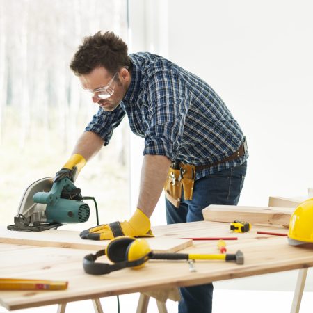 Carpenter cutting plank by circular saw